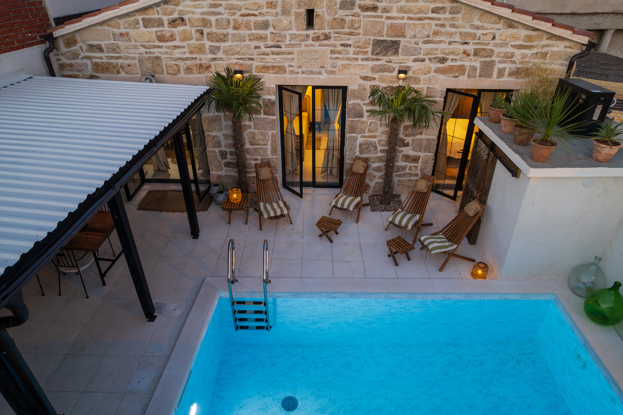 Aerial view of a Croatian stone-villa pool courtyard at dusk, a private off-site working venue