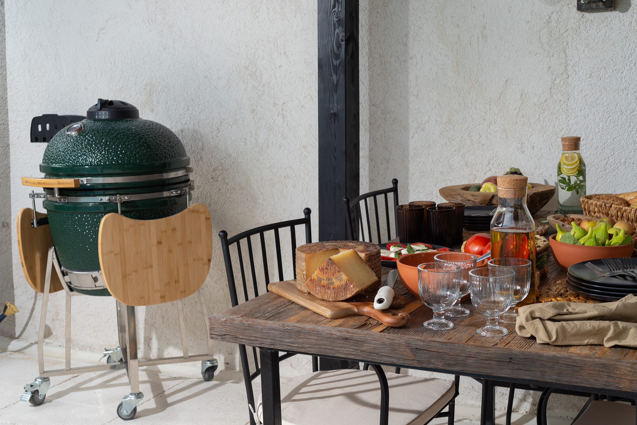 A slow lunch table set under a pergola with a kamado grill and local Croatian produce