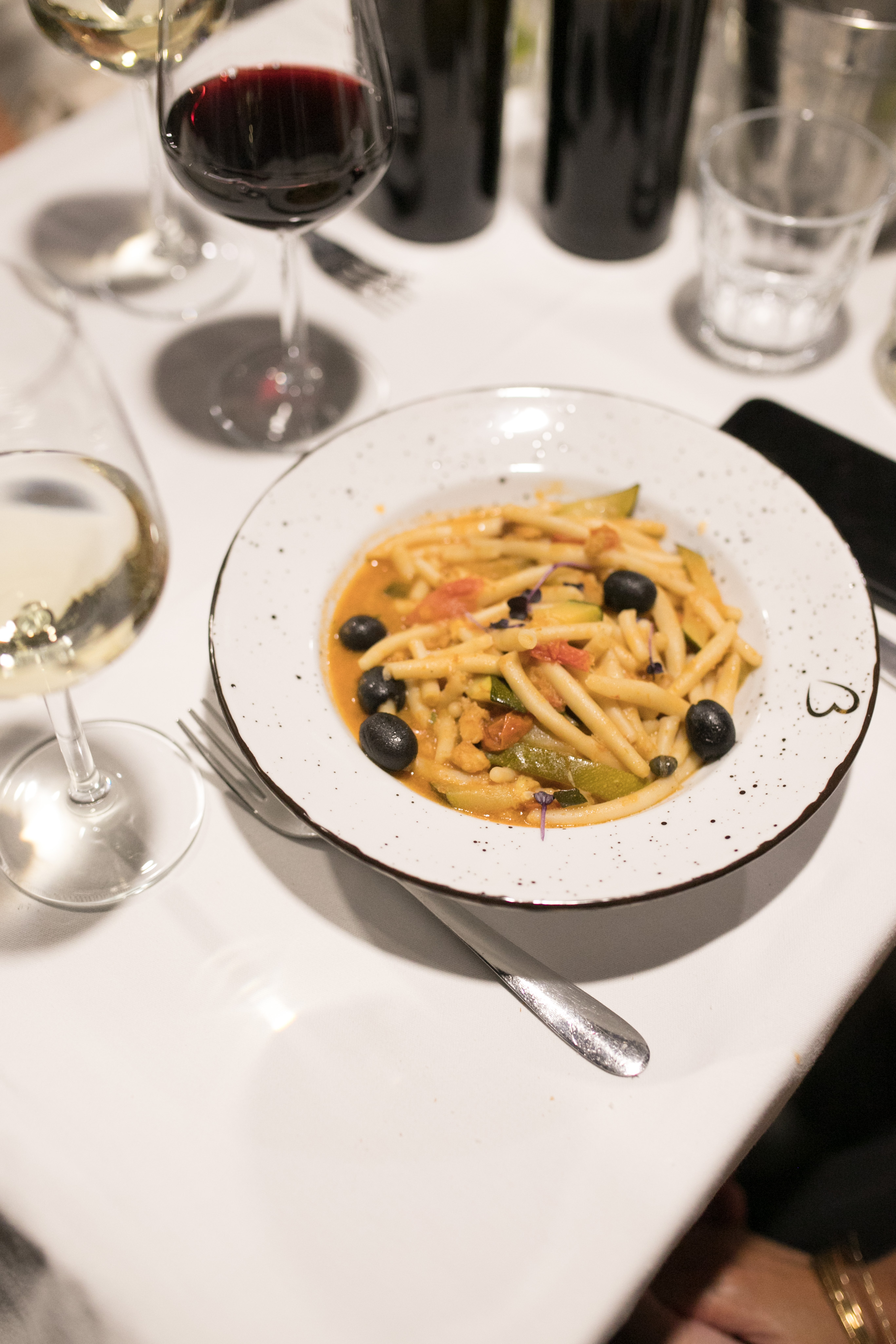 A bowl of Croatian fuži pasta with olives and zucchini paired with wine
