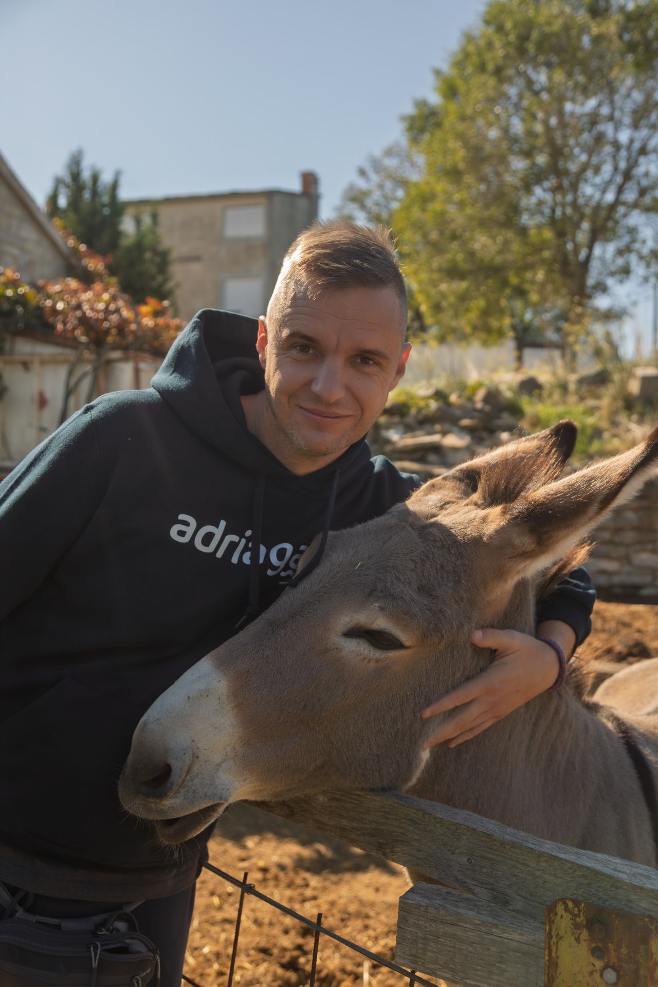 An Adriagate guest hugging a donkey at OPG Ćusa during a team-building visit