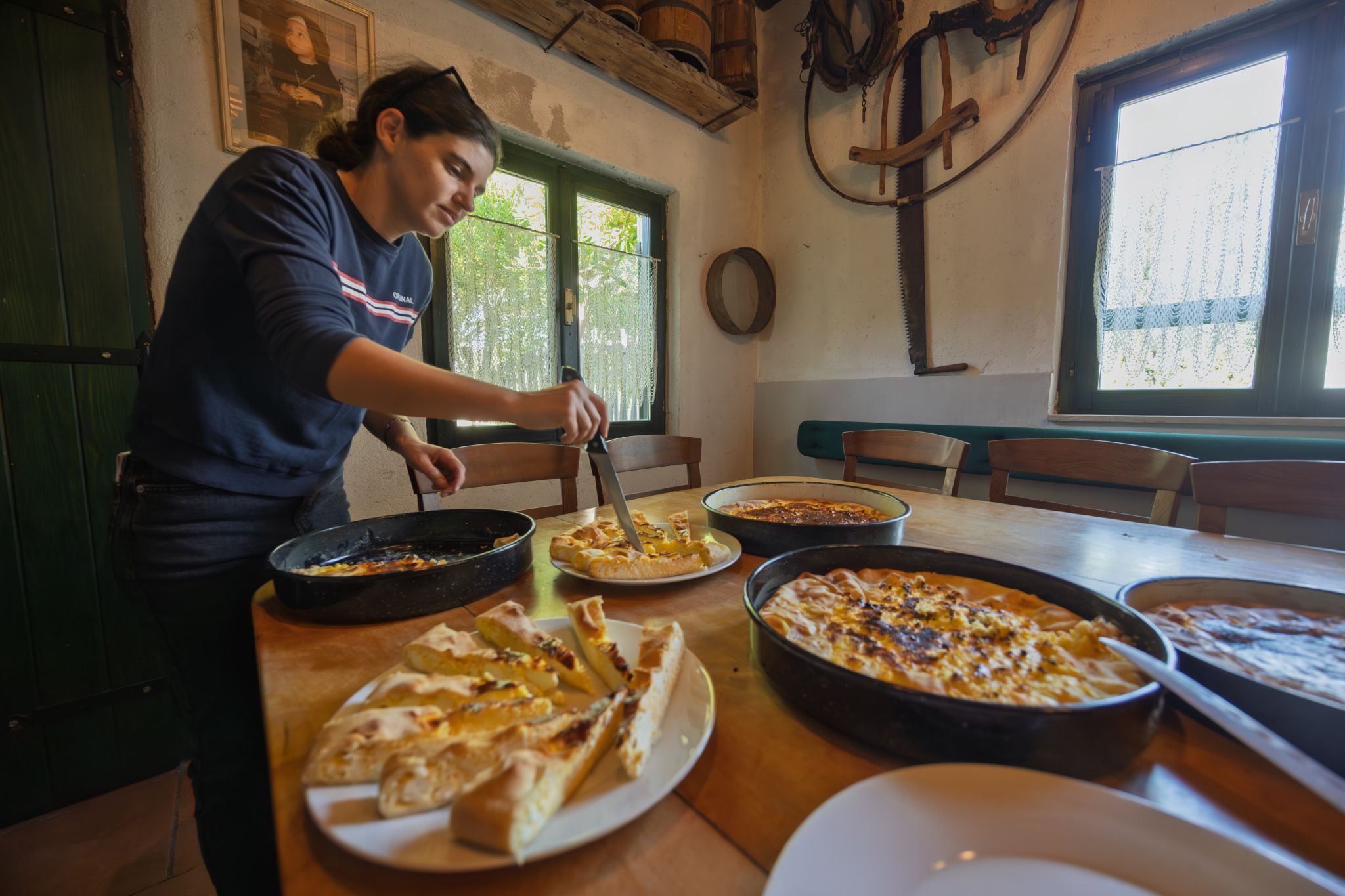 Host slicing traditional Croatian prisnac and sweet pies at a konoba tasting